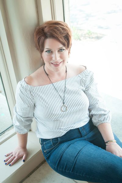 Kerry Haworth sitting in a window with a welcoming smile on her face.