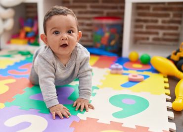 A baby crawling on a colorful foam play mat with numbers.