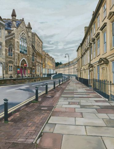 Historic street with stone buildings and patterned pavements.