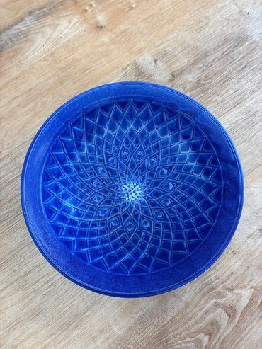 Blue plate with an intricate geometric pattern on a wooden surface.