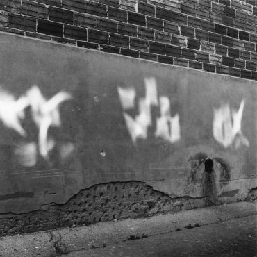 Blurred white graffiti on a worn brick and concrete wall.