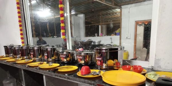 A buffet setup with stainless steel containers and yellow plates on a counter.