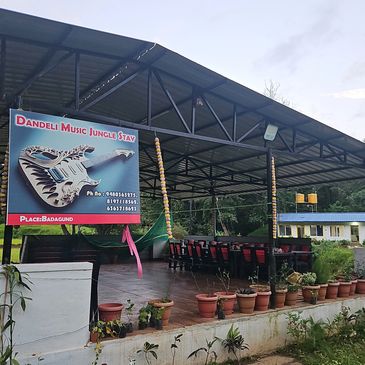 Outdoor seating area at Dandeli Music Jungle Stay with guitar-themed sign.