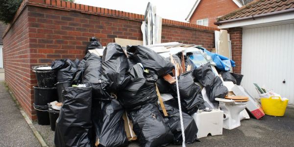 Pile of black garbage bags and household waste outside.