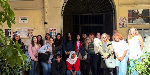 Grupo diverso de personas posando frente a un edificio.