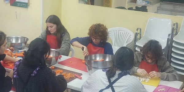 Personas cortando verduras en una mesa.