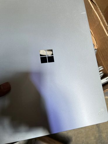 Silver Microsoft Surface device with reflective logo held by a hand.