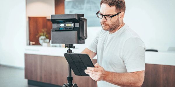 Man operating a 3D scanner with a tablet indoors.