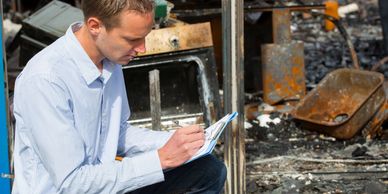 Man inspecting and documenting damage at a fire-damaged site.