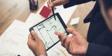 Professionals discussing architectural plans on a tablet.