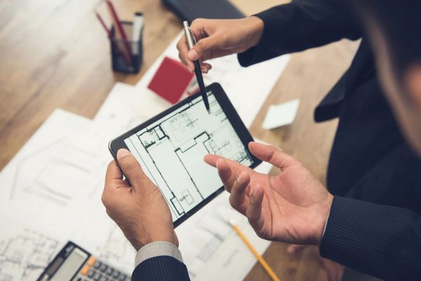 Professionals discussing architectural plans on a tablet.