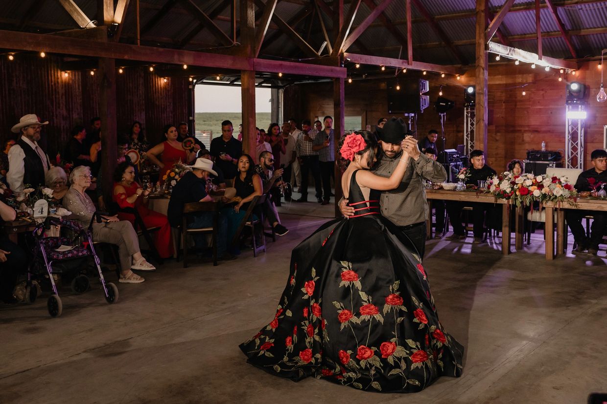 Couple dances in a decorated hall with guests watching.
