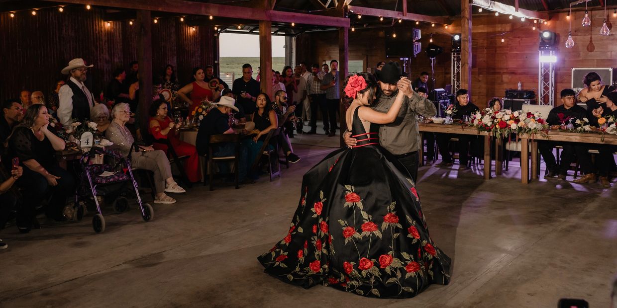 Couple dances in a decorated hall with guests watching.
