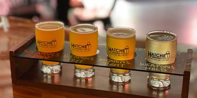 A flight of beers from Hatchet with the logo on them.