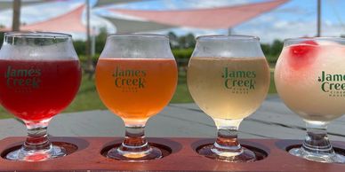A flight of ciders from James Creek with their logo on them.