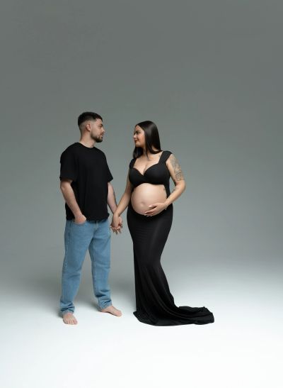 Pregnant woman and partner holding hands, looking at each other.