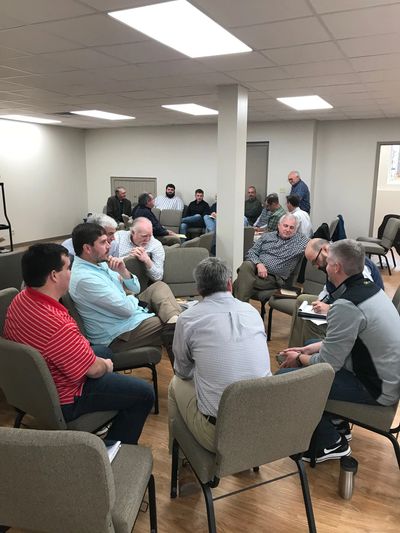 A group of men engaged in a discussion in a meeting room.