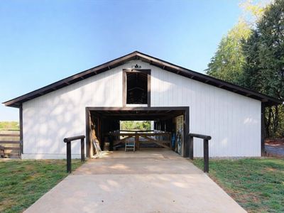 White barn with black trim and ramp entrance in a rural setting.