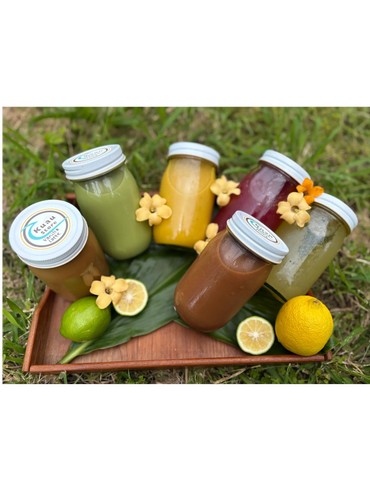 Colorful bottled drinks with flowers and fruits on a wooden tray outdoors.