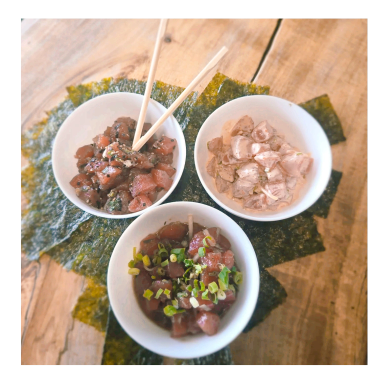 Three bowls of poke with seaweed on a wooden table.