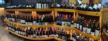 Wooden shelves stocked with a variety of wine bottles in a store.