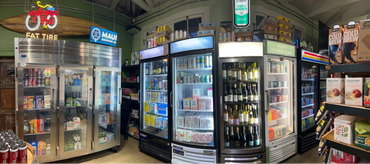 A store aisle with multiple refrigerators stocked with beverages and a neon Fat Tire bike sign.