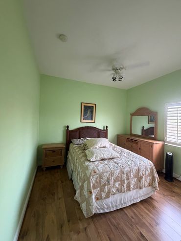 Bedroom with light green painted walls, white ceiling and a ceiling fan.