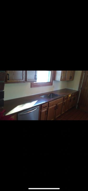 Updated kitchen countertop and sink installation with refinished wood cabinetry.