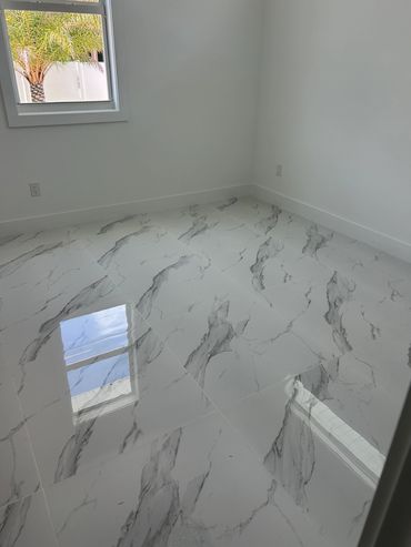Large-format marble-look tile installed on a bathroom shower wall.
