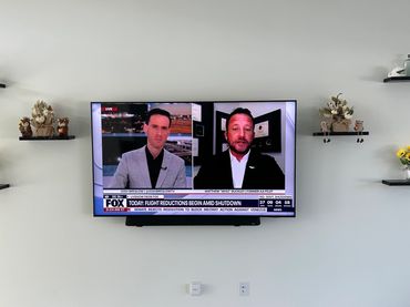 Wall-mounted television with custom floating shelves and clean cable management.