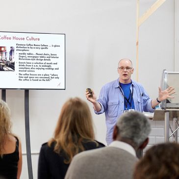 Jonathan Morris making presentation at a coffee festival with audience members and LCD screen