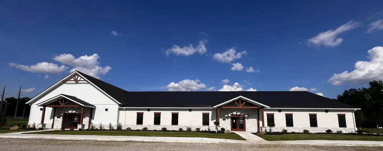 Modern white building with dark roof under a clear blue sky.