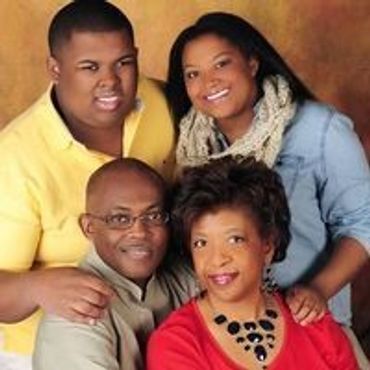 A smiling family of four posing together in warm tones.