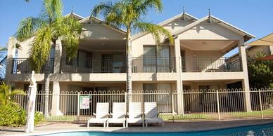 Villa with pool and palm trees under clear sky.