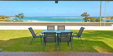Outdoor patio table and chairs with a sea view on a sunny day.