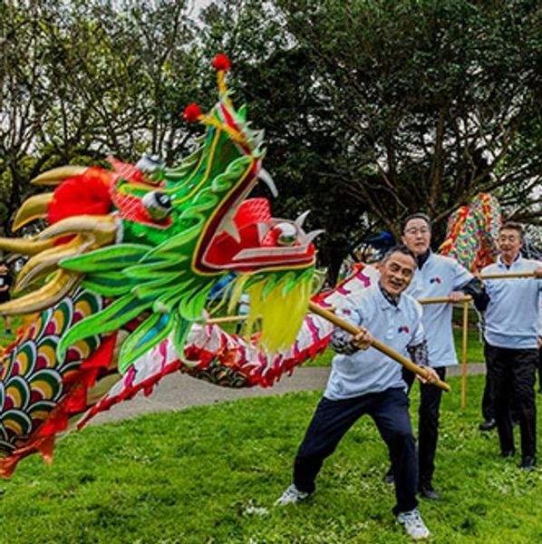 People performing a traditional dragon dance outdoors.