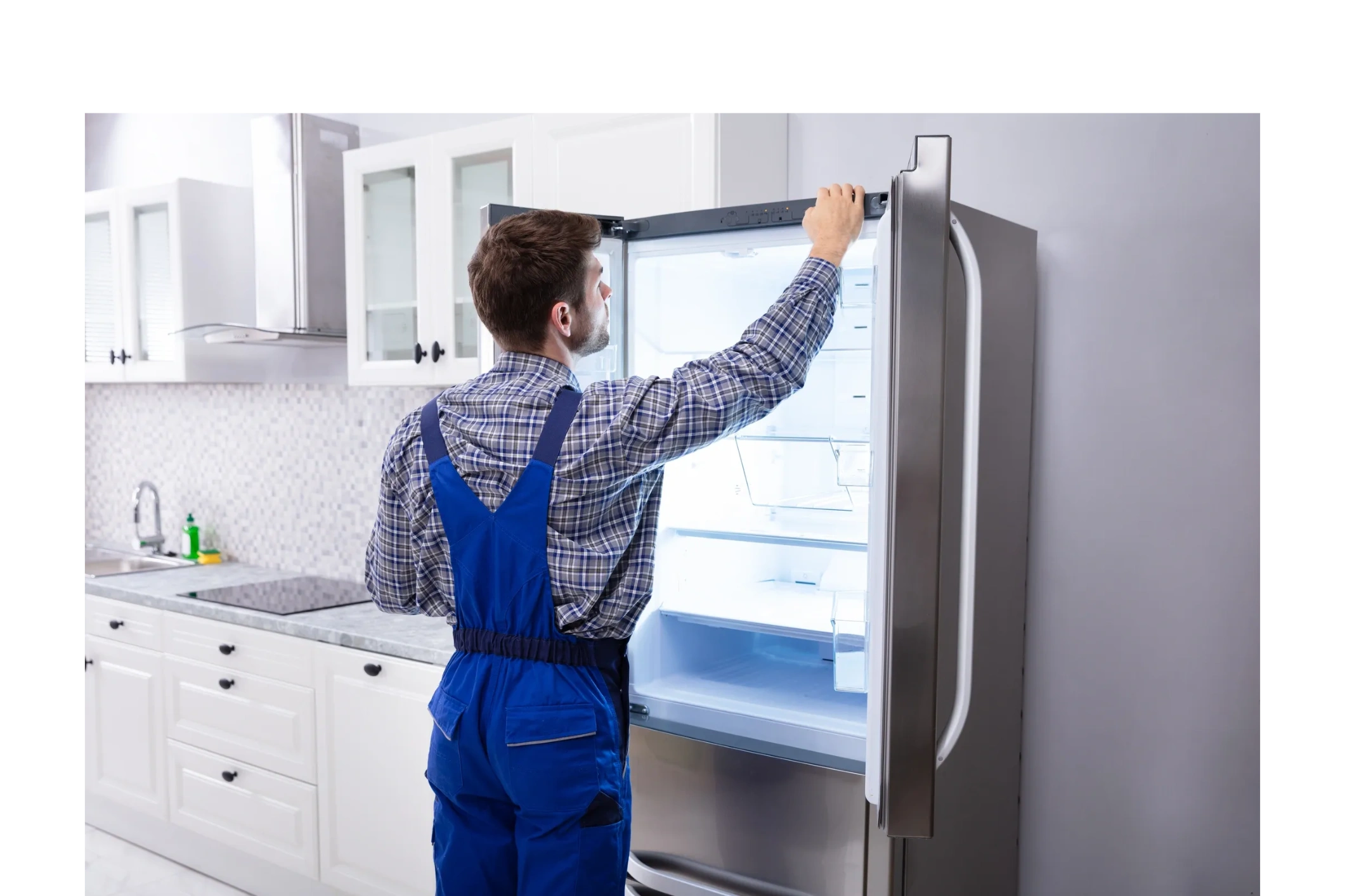 Technician inspecting an open refrigerator in a modern kitchen.