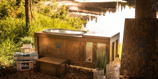 Handcrafted Tundra Tub Cold Therapy plunge placed alongside a river in an outdoor spa setting.