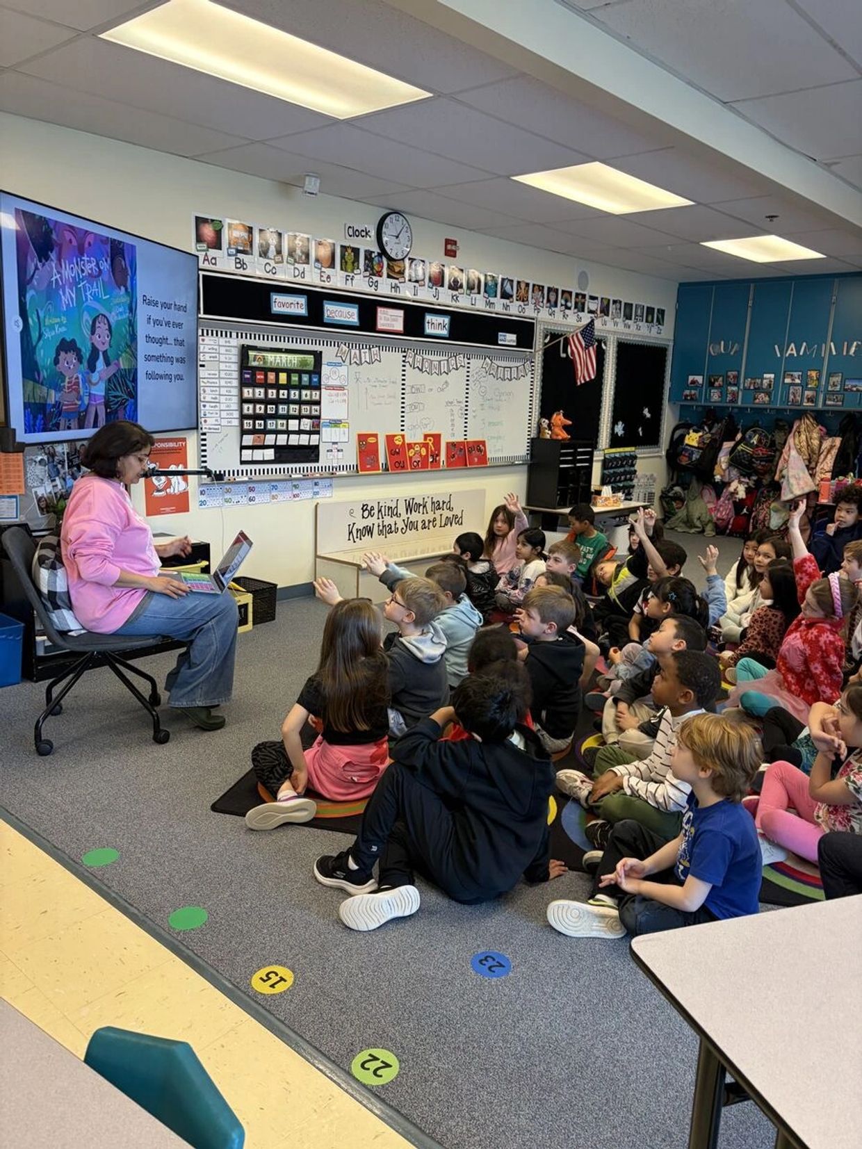 Teacher reading to engaged elementary students sitting on the classroom floor.