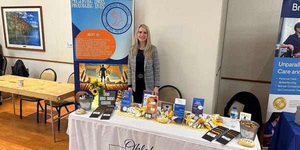 Woman standing behind an informational booth about preserving lives and health.
