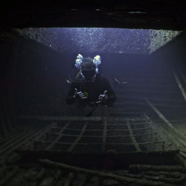 A scuba diver explores a sunken shipwreck underwater.