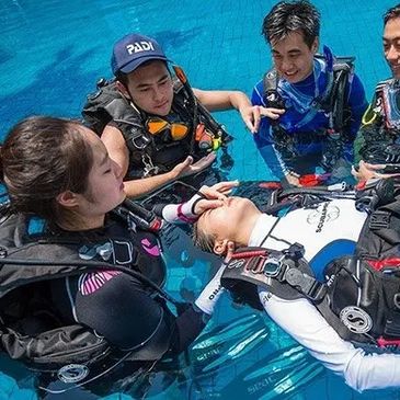Group practicing scuba rescue in a pool with one person floating.