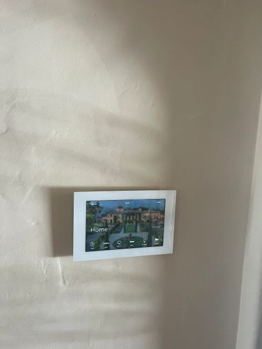 Wall-mounted smart home control panel displaying home interface.