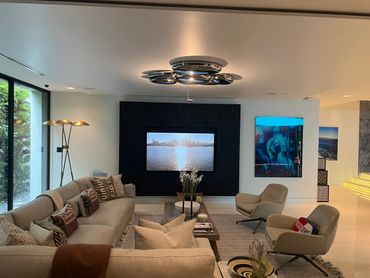 Modern living room with beige sofa, leather chairs, and wall-mounted TV.