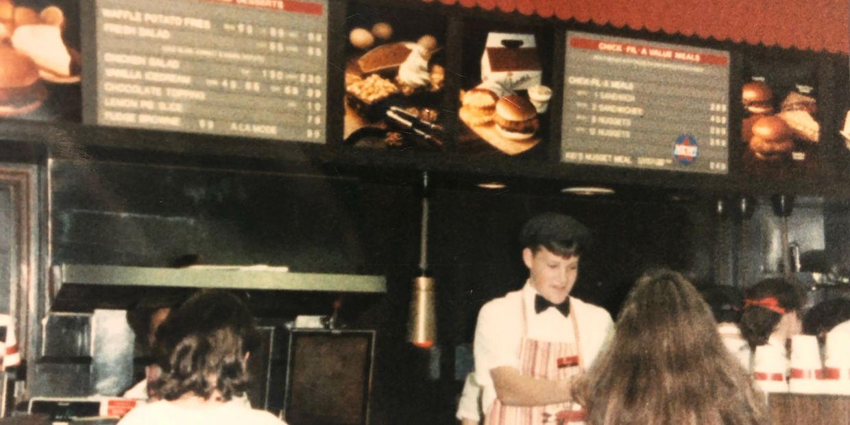 Vintage fast food restaurant counter with workers serving customers.