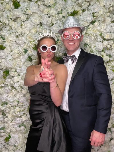 Elegant and playful photo booth experience with flower wall backdrop at a Tampa wedding