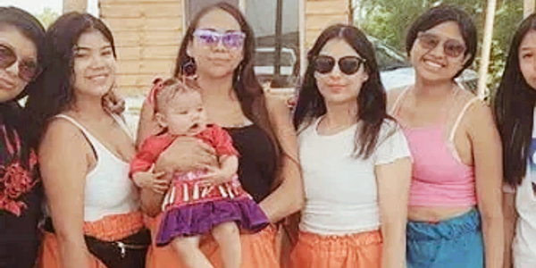 Group of women and baby posing outdoors in casual summer clothes.