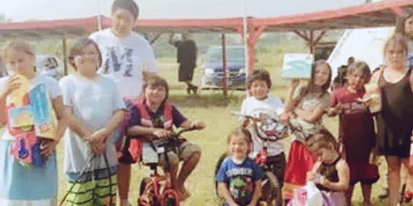 Group of children outdoors with bikes and toys.