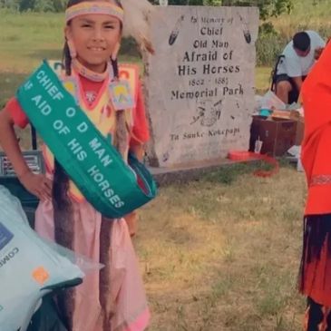 Young girl dressed in traditional attire with a sash at a memorial park.