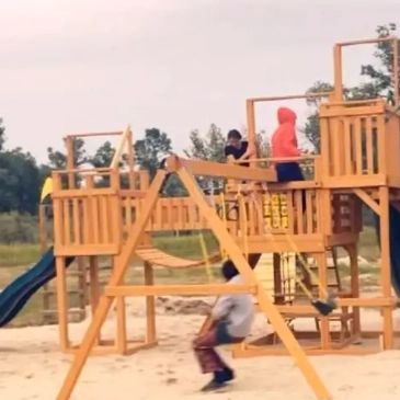 Kids playing on a wooden playground.